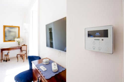 Termostato moderno che visualizza 20°C nella villetta di Meta di Sorrento, con TV e arredamenti visibili