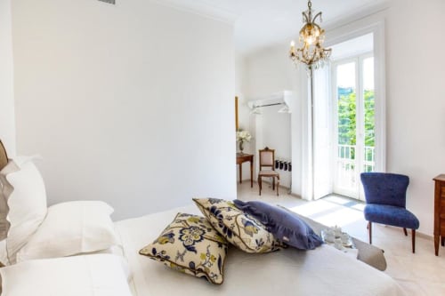 Camera luminosa al Relais Palazzo Cacace di Sorrento con arredi eleganti e vista sul giardino attraverso le porte-finestre