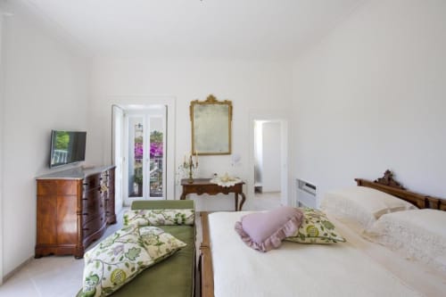 Camera elegante al Relais Palazzo Cacace a Meta di Sorrento con vista sul giardino, arredi antichi e biancheria floreale