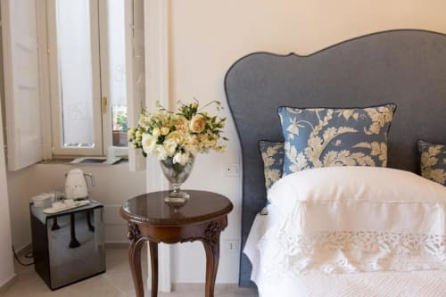 Camera elegante al Relais Palazzo Cacace a Meta di Sorrento con testata blu, biancheria bianca, fiori freschi e giardino