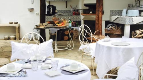 Elegante sala da pranzo del Relais Palazzo Cacace a Meta di Sorrento con tavoli con tovaglia bianca e decorazioni in ferro