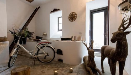Interni della cottage Relais Palazzo Cacace con scrivania bianca curva, bicicletta, sculture di cervi in bronzo e porte con vista sul giardino a Meta
