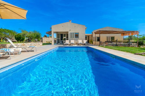 Villa de lujo en Artà con piscina azul cristalina, tumbonas y moderna terraza de piedra bajo cielo despejado