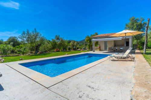 Villa moderna con piscina en Artà, agua azul, cabaña junto a la piscina, tumbonas y jardines mediterráneos bajo cielo despejado