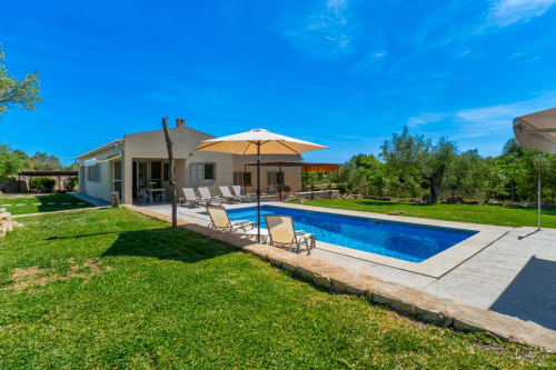 Villa moderna con piscina en Artà, España con agua azul, tumbonas, sombrilla y jardines cuidados