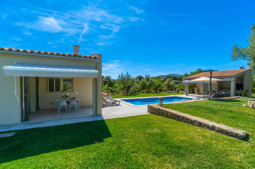 Villa de lujo en Artà con piscina, terraza, jardines frondosos y vistas a las montañas bajo cielo azul