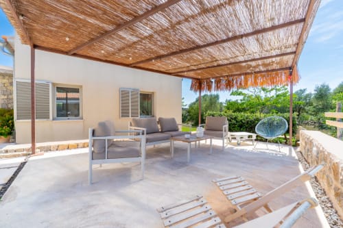 Amplio patio con asientos de descanso, pérgola de paja y vistas al campo en Artà, España