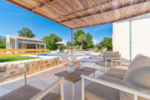 Terraza de lujo con pérgola de paja, zona de descanso y vistas a la piscina en Massa Properties, Artà