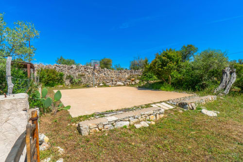 Cancha de baloncesto rústica en Massa Properties, Artà, España, rodeada de vegetación mediterránea y muros de piedra