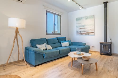Sala de estar moderna con sofá azul, piso de madera, chimenea y arte paisajístico en hotel Artà