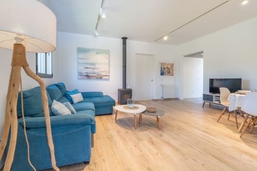 Salón moderno en Artà con sofá azul, muebles de madera, chimenea e iluminación natural en Massa Properties