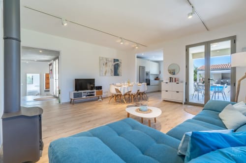 Sala de estar moderna y diáfana en Massa Properties, Artà, con sofá azul, comedor y vista al mar