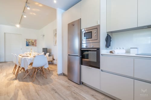 Cocina y comedor de planta abierta moderna en apartamento de Artà con electrodomésticos de acero inoxidable y pisos de madera