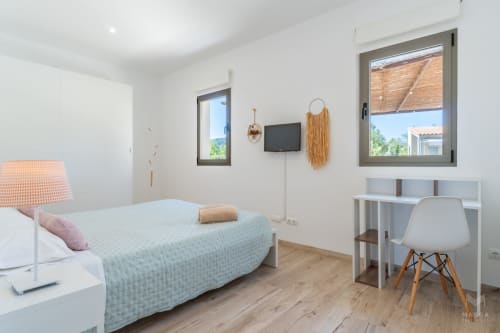 Dormitorio moderno en Massa Properties en Artà con cama, escritorio, TV y grandes ventanas con vistas al campo