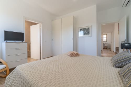 Espacioso dormitorio moderno en Massa Properties en Artà con cama king, armario empotrado, TV y baño en suite