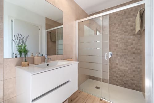 Baño moderno en Massa Properties en Artà con tocador blanco, ducha abierta y diseño de azulejos neutros