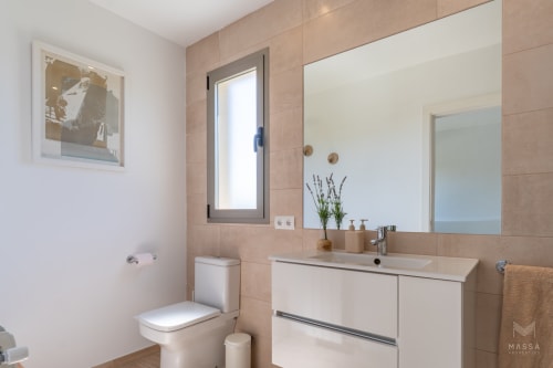 Baño moderno en Massa Properties de Artà con tocador blanco, espejo grande, azulejos beige y luz natural