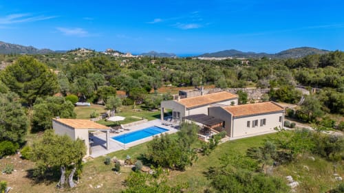 Villa moderna en Artà, España con piscina, tejado de barro, rodeada de olivos y paisaje mediterráneo