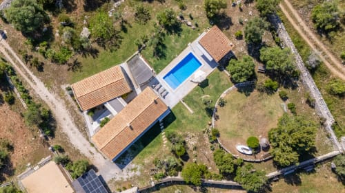 Vista aérea del hotel Massa Properties en Artà con piscina azul, tejados de barro y jardines mediterráneos