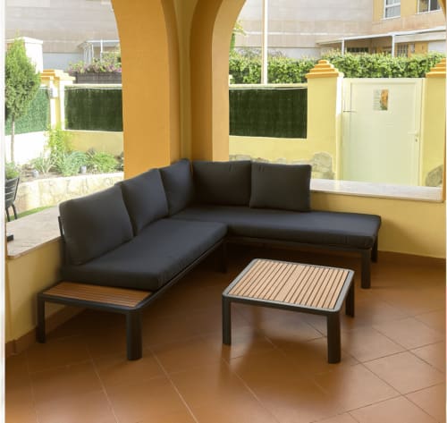 Sofá seccional negro moderno con mesa de café en la terraza del hotel El Chalecito de Alicante