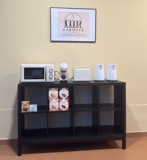 Estación de café en el hotel El Chalecito de Alicante con microondas, tostadora y bebidas en estante oscuro