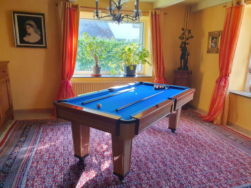 Biljartkamer van B&B Sur La Rive Vierre in Chiny met blauwe pooltafel, gele muren en rode gordijnen