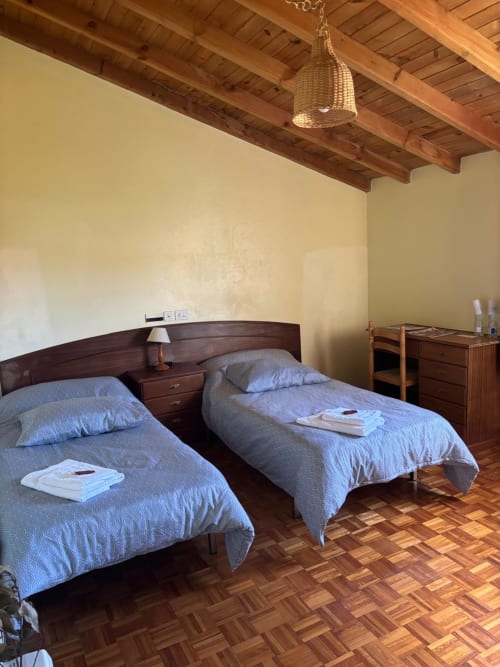 Habitación doble del Hotel O Esqueiro con vigas de madera, ropa de cama azul y suelo de parqué en Malpica