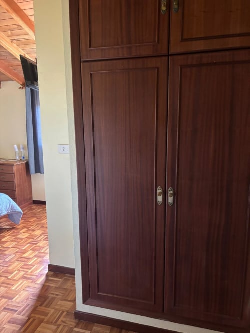 Armario de madera oscura en la habitación del Hotel O Esqueiro Corcubión con suelos de parqué y paredes blancas