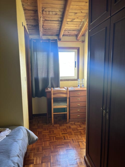 Habitación Laxe del Hotel O Esqueiro en Malpica con escritorio de madera, suelo de parqué y ventana con vistas al jardín