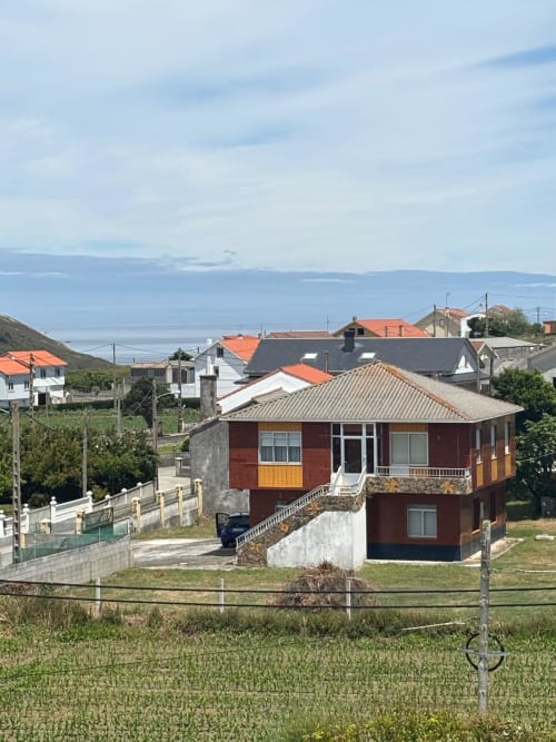 Hotel Restaurante O Esqueiro en Malpica, A Coruña - edificio de ladrillo rojo con jardín con vistas al paisaje costero