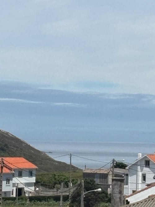 Vista del pueblo costero de Malpica desde el Hotel O Esqueiro con casas blancas, montañas y vista al mar desde la habitación