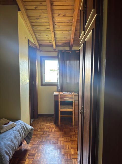 Habitación luminosa en el Hotel O Esqueiro de Malpica con techo de vigas de madera, suelo de parqué, escritorio y vistas al jardín