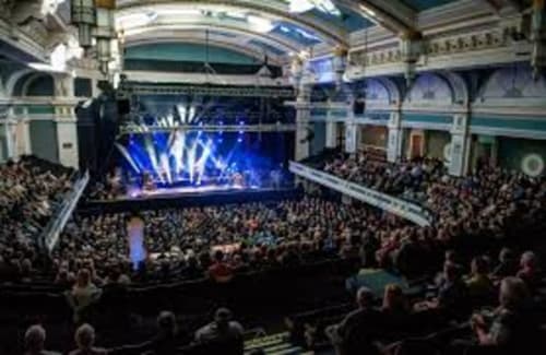 Grand concert hall at JS Apartments Collection in Blackburn with full audience and blue stage lighting