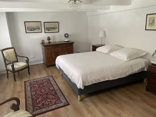 Spacious bedroom at Ferme Freysz with queen bed, striped chair, wooden furnishings, and classic décor in Quatzenheim, France