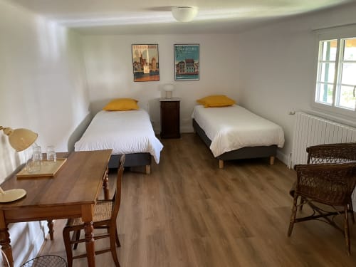 Bright bedroom at Ferme Freysz B&B in Quatzenheim with two single beds, yellow pillows, wooden desk, and garden views through