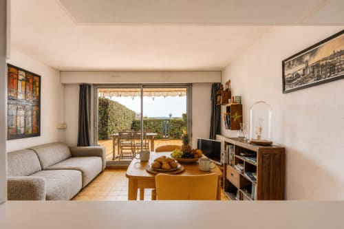 Lumineux séjour de l'appartement à Cap Ferret avec terrasse vue mer, canapé arrondi, table en bois et salon extérieur à La