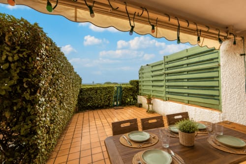 Terrasse de La Loge Du Bassin avec table dressée, paravents de verdure et haies à Lège-Cap-Ferret