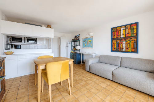 Espace de vie ouvert avec cuisine, table à manger avec chaise jaune et canapé gris dans un appartement à Cap Ferret
