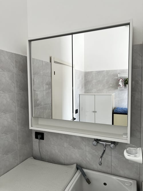 Modern bathroom with gray tile walls, white vanity sink, and large mirrored cabinet in WelcHome Miramare apartment,