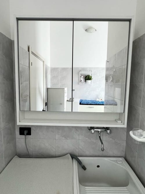 Modern bathroom at WelcHome Miramare apartment in Fossacesia with tiled shower, white sink, and large mirror