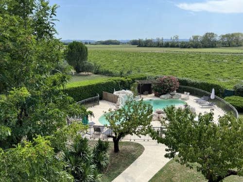 Piscine turquoise de La Bastide des Princes à Caderousse, entourée de jardins luxuriants et de vues sur la campagne