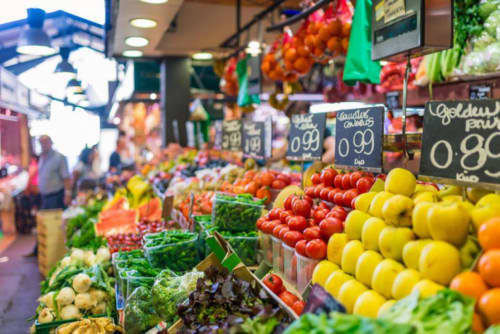 Colorful produce display at local market in Pornic featuring fresh vegetables, tomatoes, and lemons with price signs