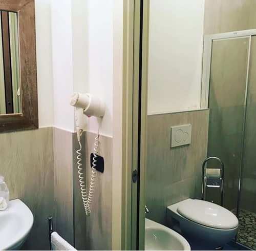 Moderno bagno dell'hotel La Finestra sul porto con toilette, bidet, telefono a parete e box doccia con portasciugamani