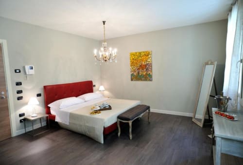 Camera moderna a La Finestra sul porto a Cesenatico con letto rosso, lampadario e pavimenti in legno