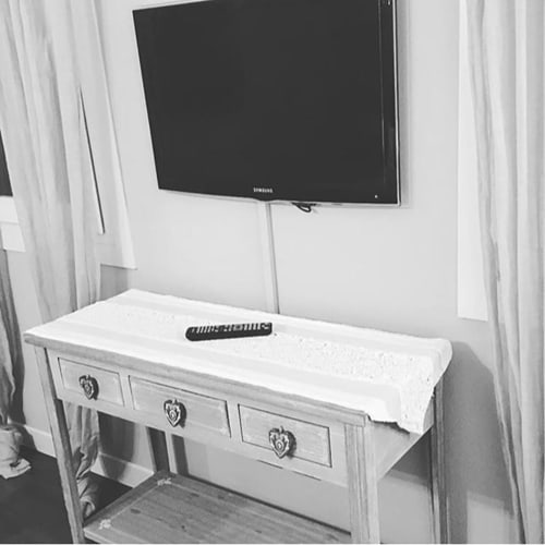 TV Samsung a schermo piatto montato su parete bianca sopra la scrivania con telecomando nella Stanza Tripla Mia presso La Finestra sul porto
