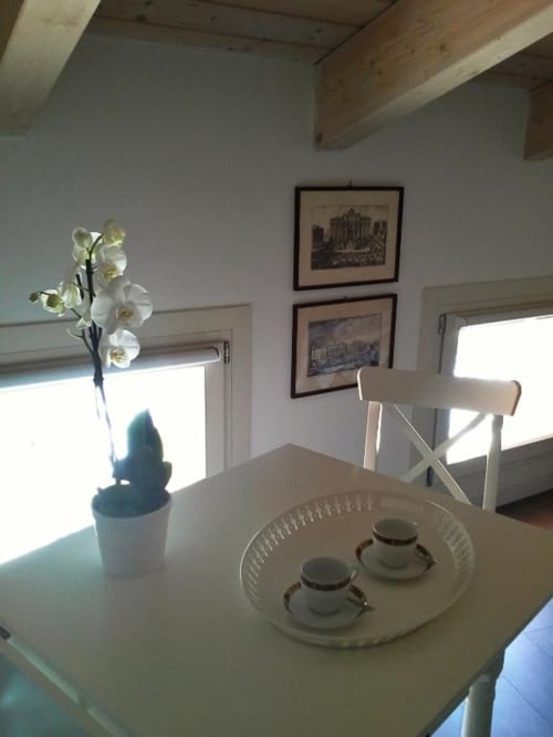 Luminosa zona pranzo nella Fiorella Superior Triple Room de La Finestra sul porto a Cesenatico, con orchidee bianche e vista mare