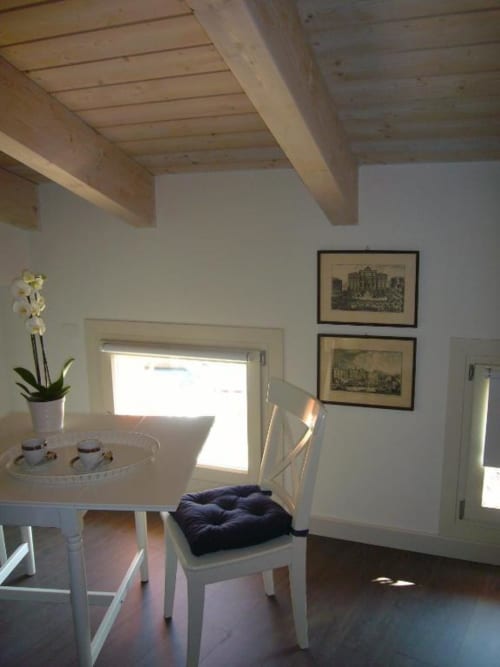 Luminosa sala da pranzo nella Suite Tripla Superior Fiorella di La Finestra sul porto, Cesenatico, con tavolo rotondo bianco e arredamenti in legno