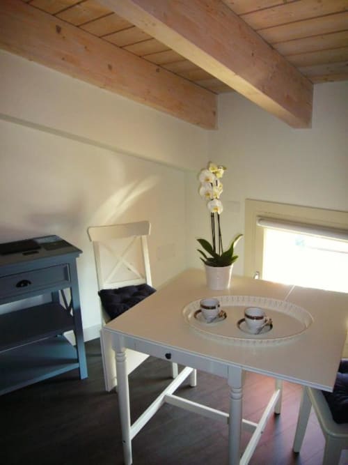 Luminosa zona pranzo nella Triple Room Fiorella Superior di La Finestra sul porto, Cesenatico, con tavolo bianco, sedia e orchidea