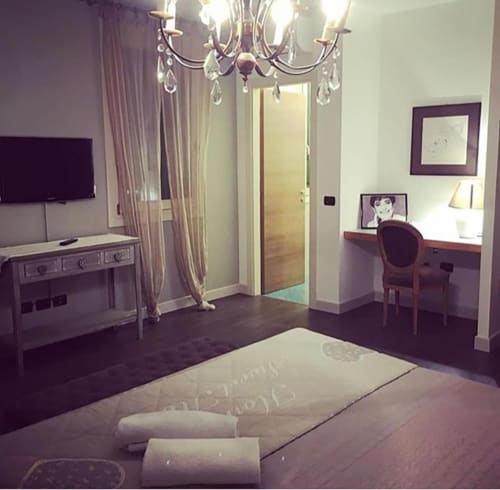 Camera elegantemente arredata a La Finestra sul porto B&B a Cesenatico con pavimenti in legno, lampadario di cristallo, TV e