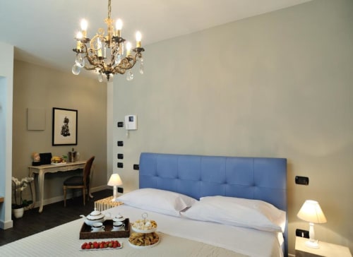 Elegante camera da letto presso La Finestra sul porto B&B a Cesenatico con testata imbottita blu, lampadario in cristallo e zona di lavoro